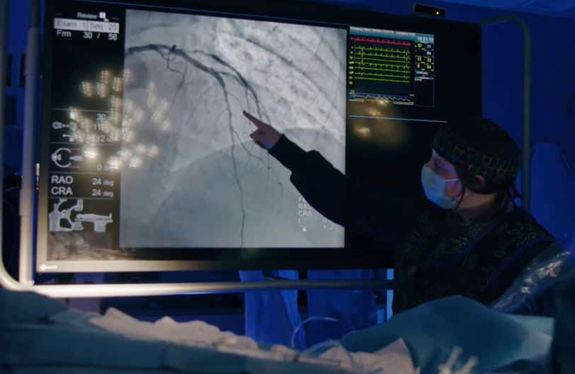 A physician examines an image of a heart.